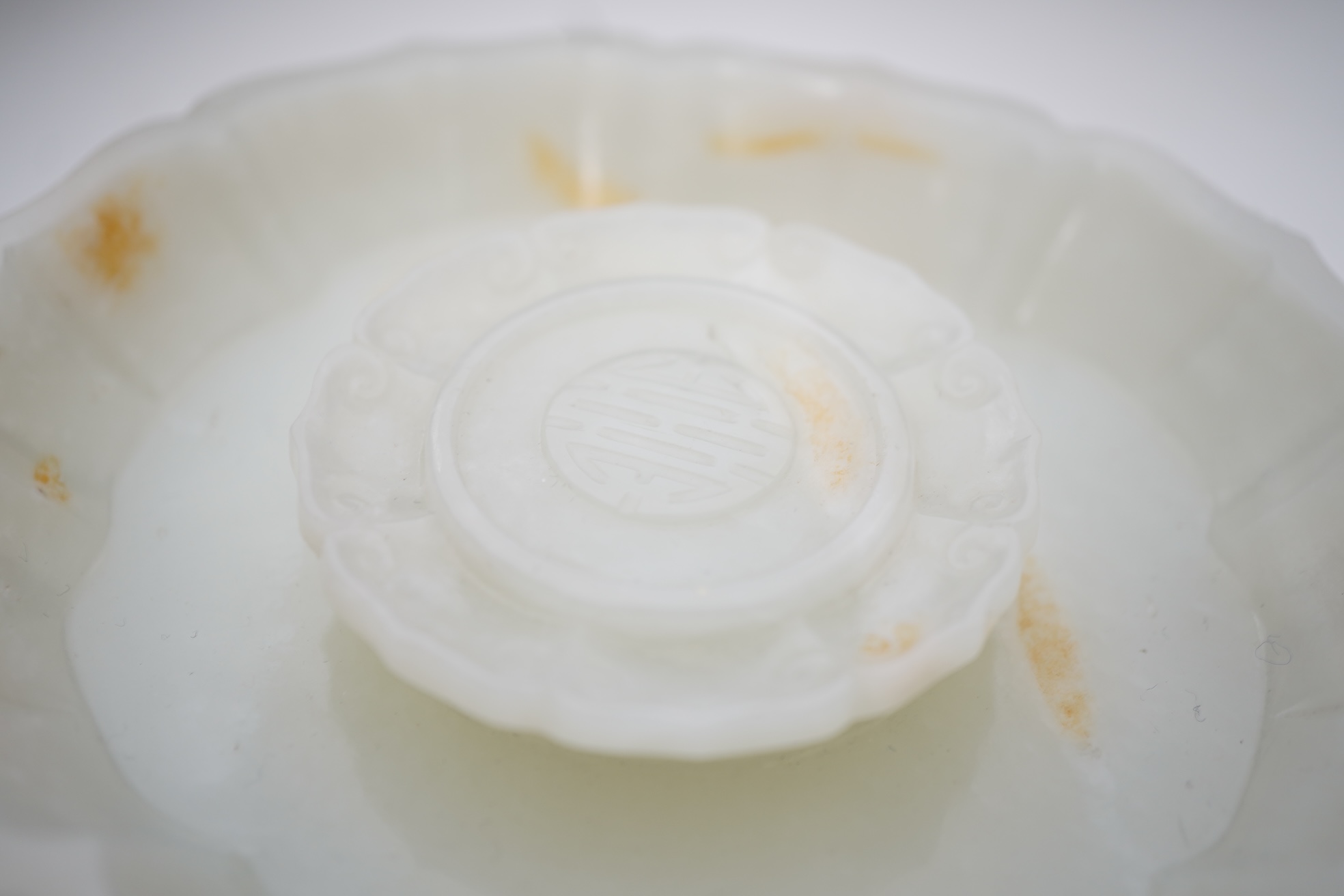 A Chinese white and russet jade petal lobed cup stand